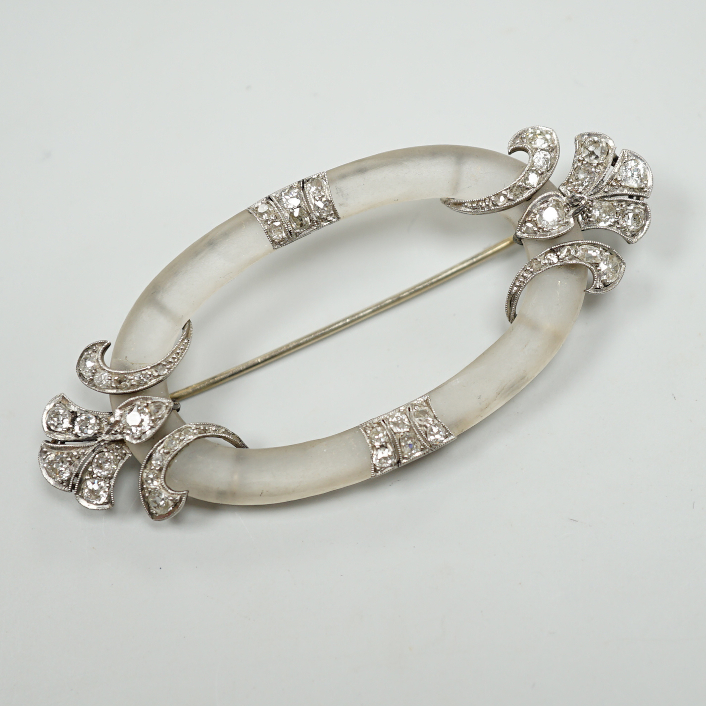 A Belle Epoque diamond set platinum and frosted brooch of open oval form with stylised foliate terminals, width 7cm